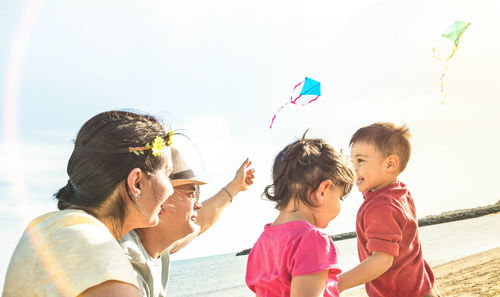 Family enjoying at beach against sky