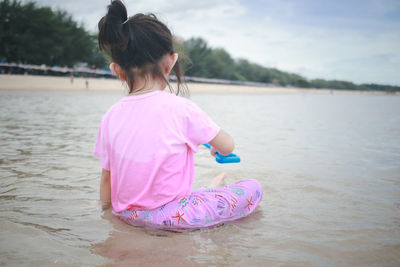 Cute girl sit on beach and look at sea