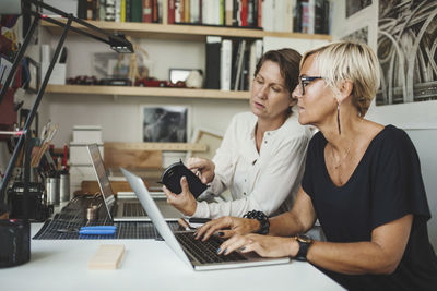 Female designers discussing over solar product at home office