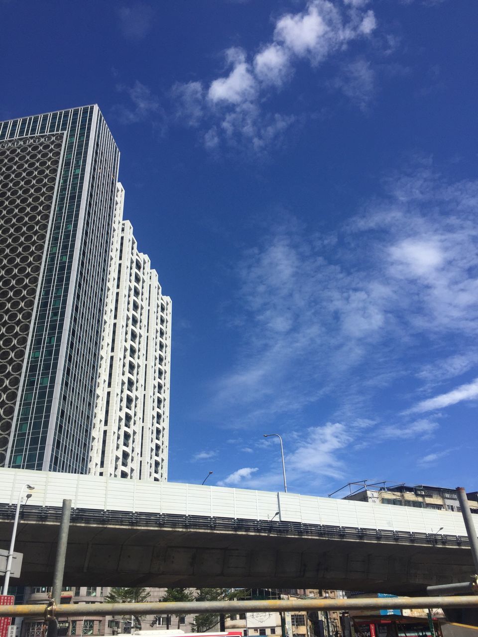 building exterior, architecture, city, low angle view, built structure, sky, skyscraper, tall - high, office building, modern, blue, tower, cloud, day, building story, outdoors, city life, development, cloud - sky, apartment, financial district, urban skyline