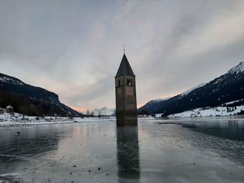 Tower amidst buildings against sky during winter