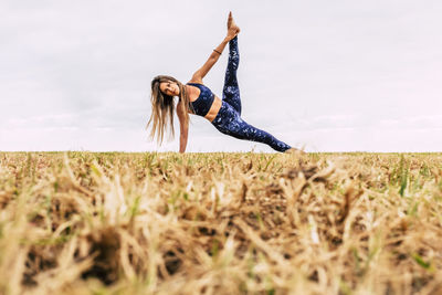 Woman with arms raised on field against sky