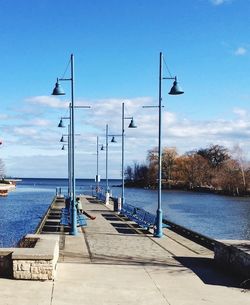 View of walkway lined with benches leading to sea