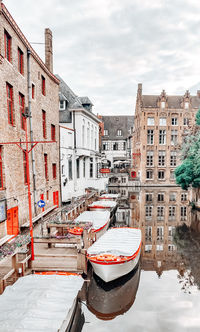 Boats in canal amidst buildings in city against sky