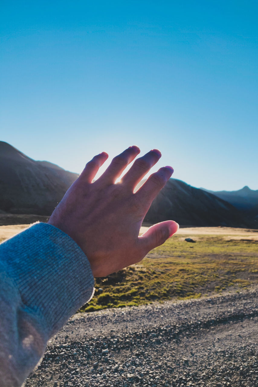 MIDSECTION OF PERSON AGAINST BLUE SKY AND MOUNTAIN