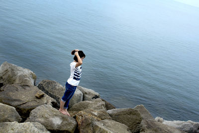 Side view of woman standing on rock by sea