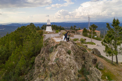 People standing on rock against built structure and sky