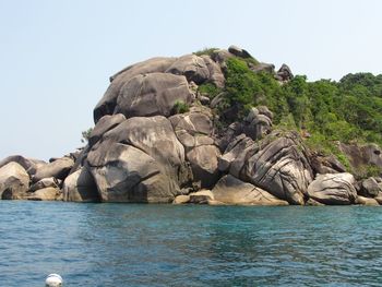 Rock formation in sea against clear sky