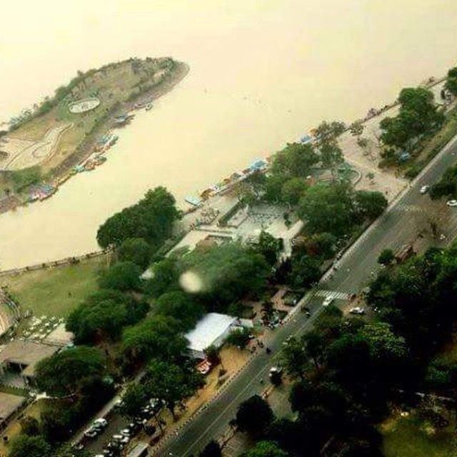 high angle view, tree, road, mountain, water, transportation, built structure, building exterior, architecture, landscape, aerial view, sea, scenics, car, nature, city, sky, beauty in nature, tranquil scene, tranquility