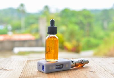 Essential oil in bottle over electronic cigarette on table