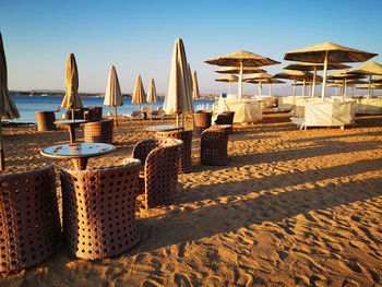 Hooded chairs on beach against sky