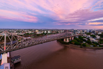 Bridge over river amidst buildings in city against sky