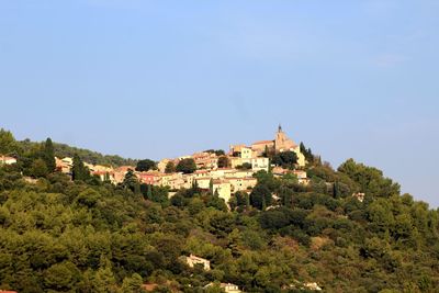 Buildings by trees against clear sky