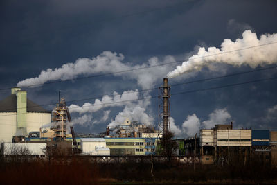 Smoke emitting from factory against sky