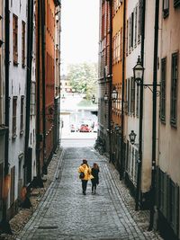 Rear view of people walking on street amidst buildings