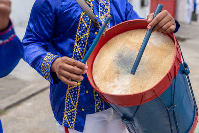 Members of a marujada, dressed in blue, play percussion instruments 