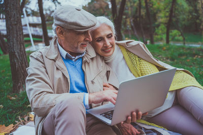 Midsection of man using mobile phone while sitting outdoors