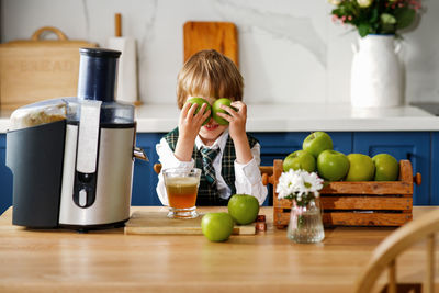 Cute schoolboy makes fresh apple juice for breakfast. vitamins and healthy nutrition for schoolers