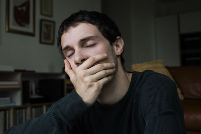 Upset boy with hand covering mouth at home