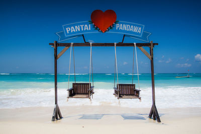 Swings on shore at beach against sky