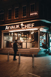 Full length of man standing on illuminated street at night