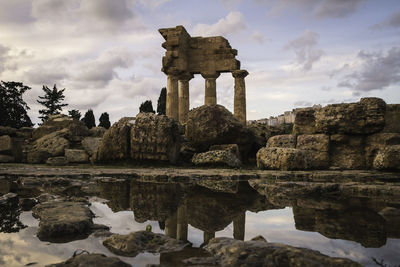 Old ruins by lake against sky