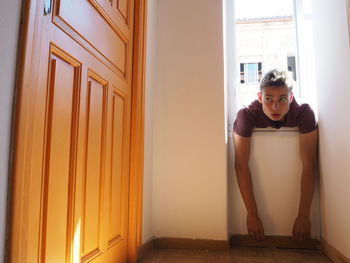 Man leaning on window sill at home