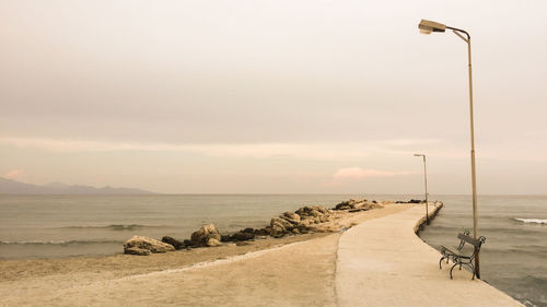 Street by sea against sky during sunset