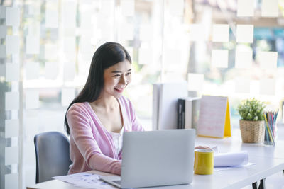 Woman looking away while sitting on table