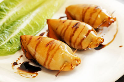 Squid stuffed with prepared stuffing and baked photographed in the studio on a white plate.