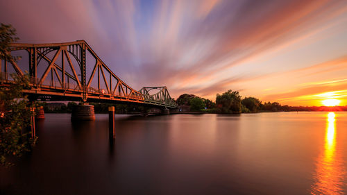 Glienicke bridge over river havel against sky during sunset