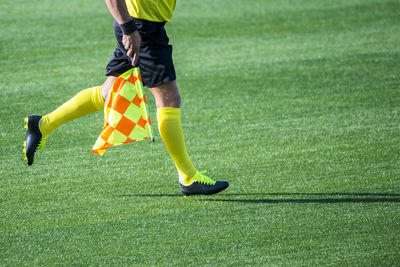 Low section of referee with flag running on soccer field