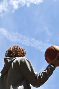 Rear view of woman playing basketball while sitting on stage