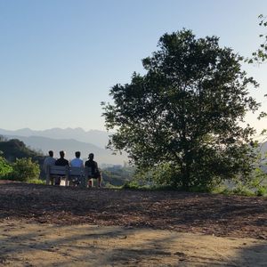 People relaxing on mountain against clear sky