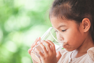 Close-up of girl drinking water from glass outdoors