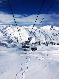 Ski lift over snowcapped mountains against sky