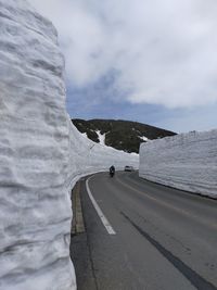 Rear view of man walking on road against sky