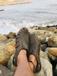 Low section of person relaxing on rock at beach