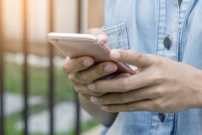 Midsection of man holding mobile phone