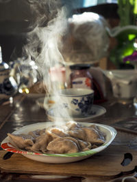 A plate of mouth-watering hot dumplings, steam rises above the plate, illuminated by the  sunlight