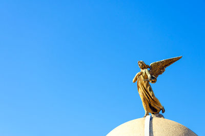 Low angle view of angel statue at la recoleta cemetery against clear blue sky