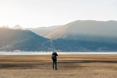 Rear view of man standing on mountain against sky