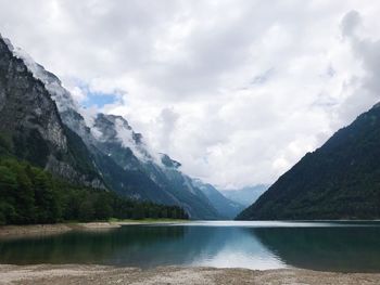 Scenic view of lake and mountains against cloudy sky