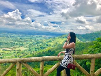 Woman standing by railing against mountain