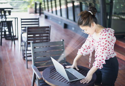 Young woman using laptop while sitting on bench