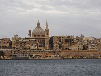 View of cityscape by sea against sky