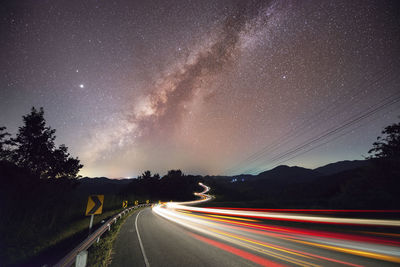 Light trails on road against sky at night