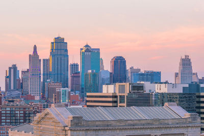 Modern buildings in city against sky during sunset