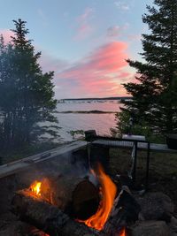 Bonfire on wooden structure against sky at sunset