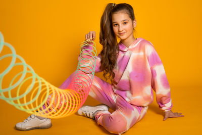 Teen girl play rainbow slinky toy on color background